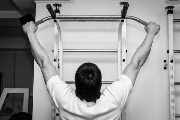 Man hanging from a pull up bar.