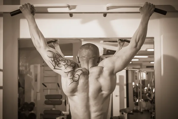 Man with a tattoo  exercising in gym