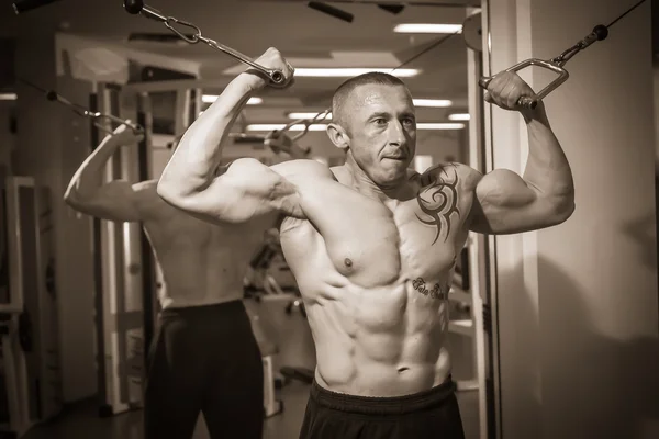 Man with a tattoo  exercising in gym