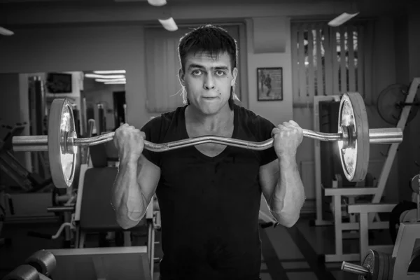 Man training with athletic barbell in gym