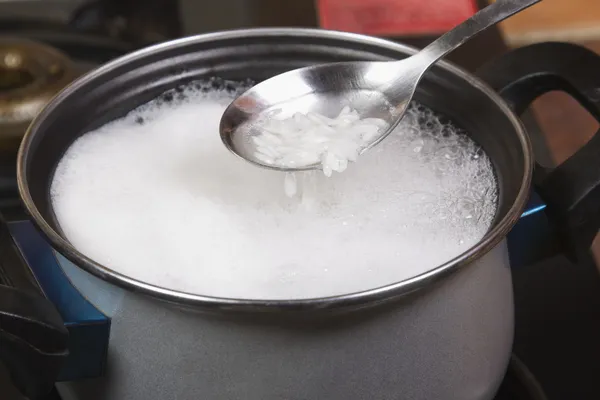 Spoon over a pan of rice boiling on a stove