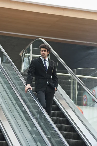 Businessman moving down on an escalator