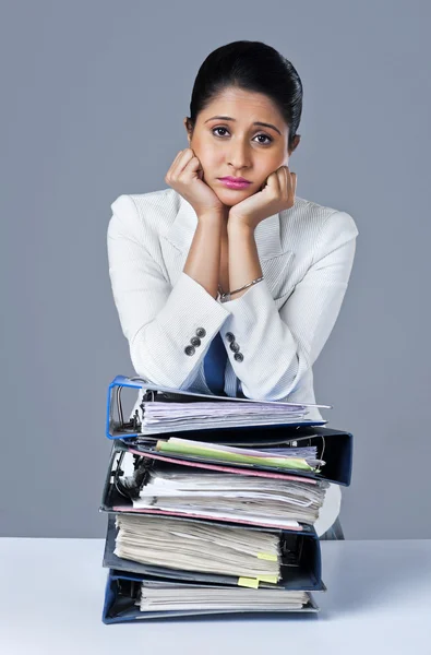 Businesswoman leaning on a stack of files