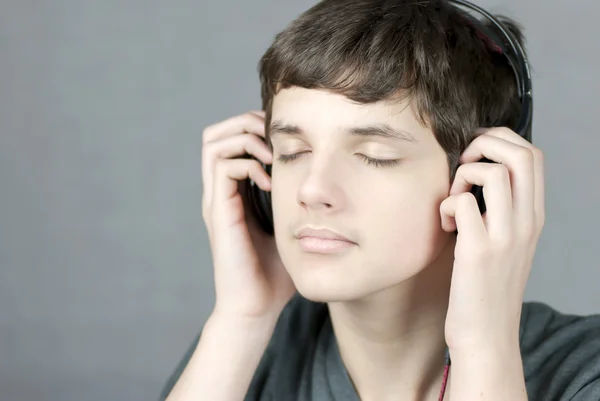 Teen Holding Headphones To Ears With Eyes CLosed