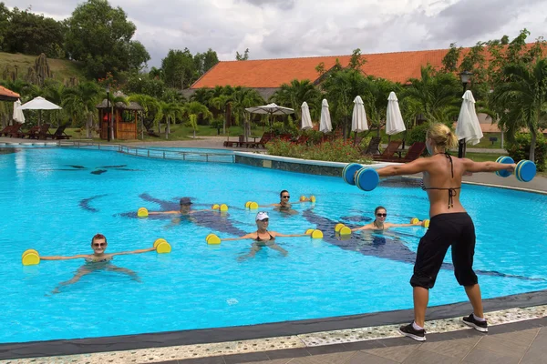 Aqua Gym aerobics fitness instructor in front of a group of people in the water performing exercises.