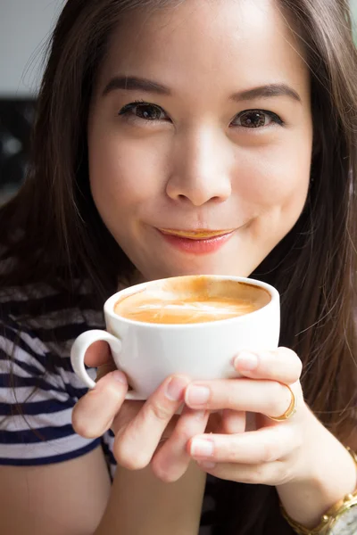 Close up of woman smiling and drinking cappuccino coffee