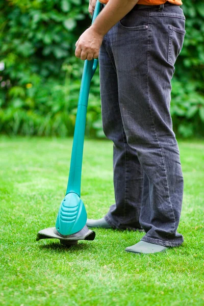Man mowing lawn with grass trimmer
