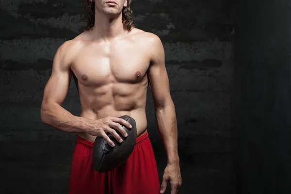 Cropped view of bare chested muscle man holding football ball in his hands — Stock Photo #31553199