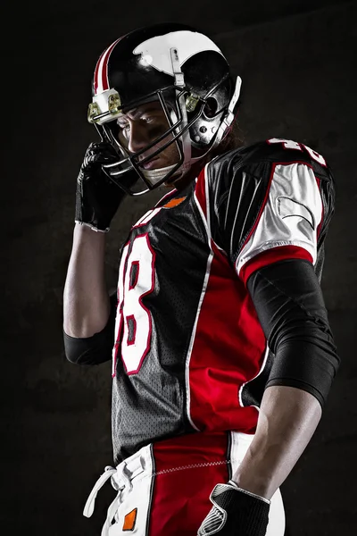 Portrait of american football player looking aside on dark background