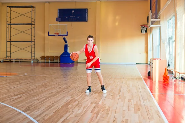Basketball player with a ball in his hands and a red uniform.
