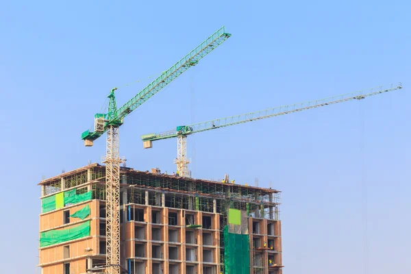 Construction site with crane and workers on blue sky