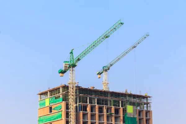 Construction site with crane and workers on blue sky