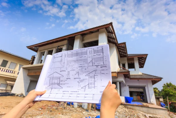 Architecture drawings in hand on big house building