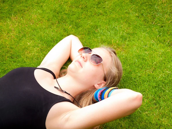 Beautiful Teenage Girl with sunglasses lying on her back in the grass