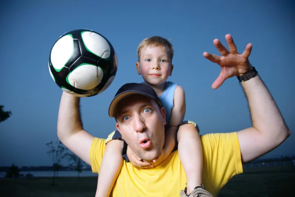 Dad and son playing football outdoors