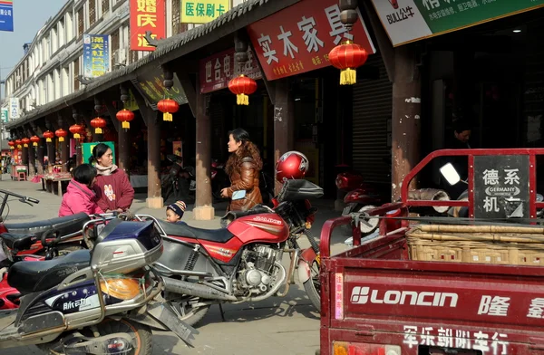 Jun Le, China: Women Chatting in Front of Stores