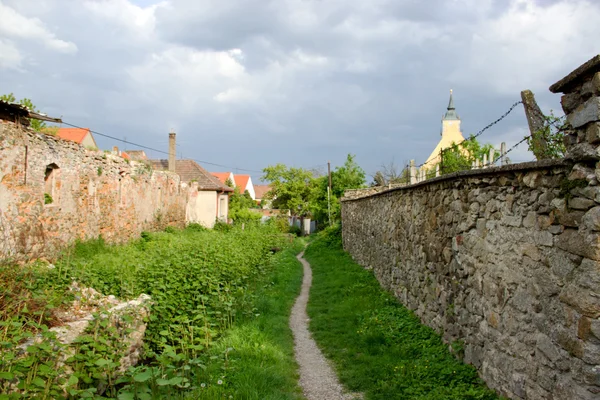 Old Romantic Bypath Covered by Flowers with Church in Distance