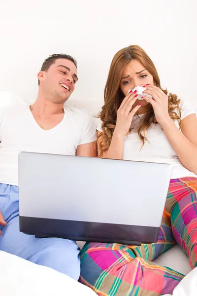 Couple watching dramatic movie in bed on laptop