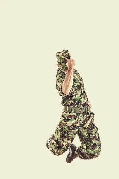 Soldier with hidden face in green camouflage uniform jumping
