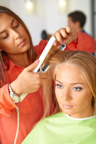 Hair salon. Woman haircut. Use of straightener.