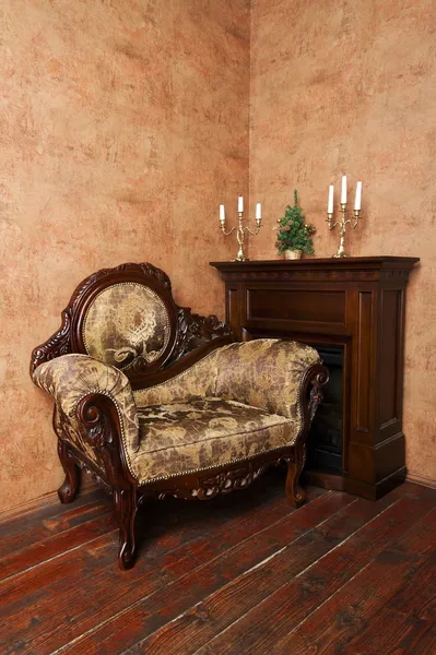 Old fashioned interior with luxury armchair, fireplace, candelabras and small Christmas tree