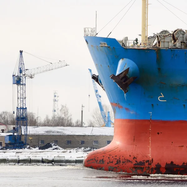 Cargo ship's bow heading forward against port cranes