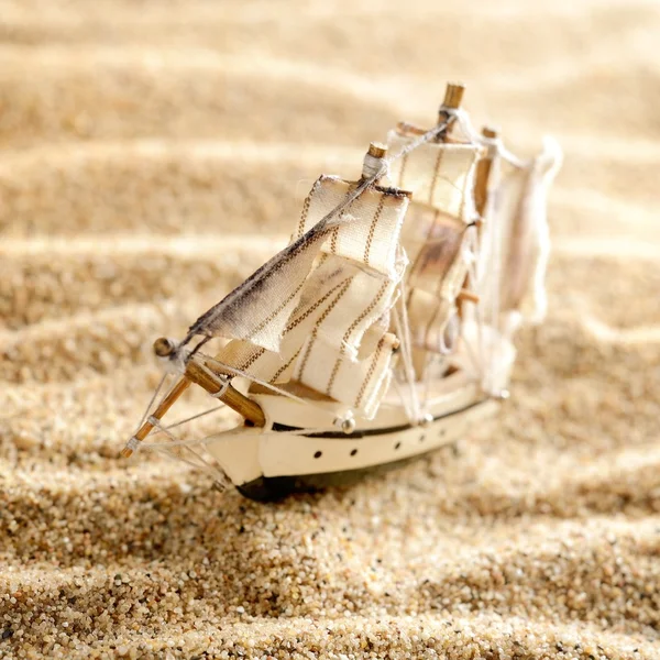 Wooden sail ship toy model in the sea sand close-up