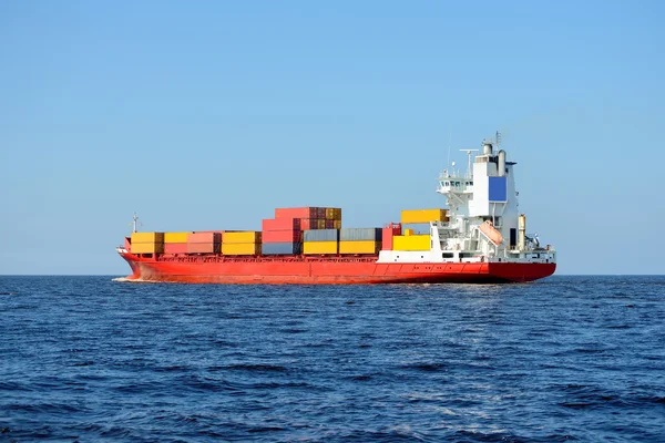 Red containership loaded with colorful cargo containers at the s