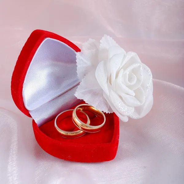 Two wedding rings in red case and a rose