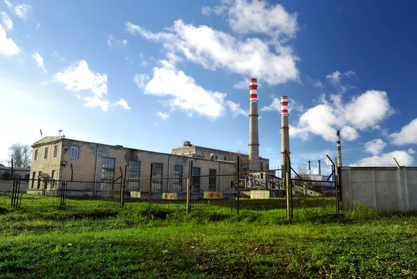 Industrial factory producing electricity with pipes against blue sky