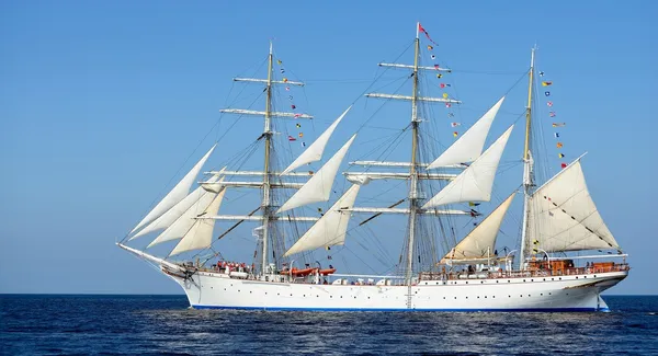 Old historical tall ship with white sails in blue sea