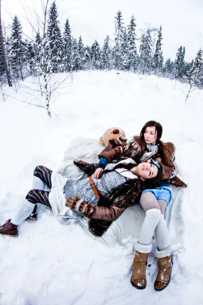 Fashion women lying on white snow winter background fisheye