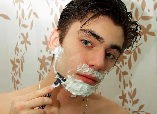 Man with shaving foam on his face and a razor in his hand