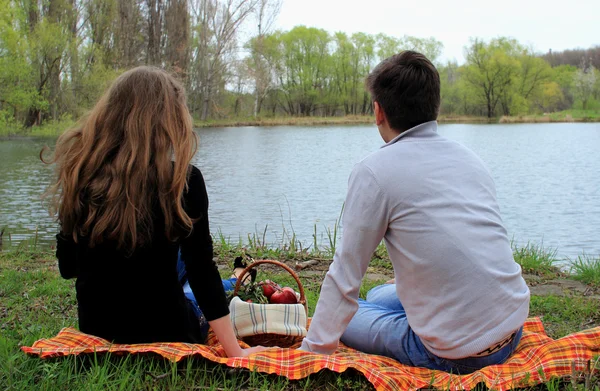Young man and woman sitting at the lake and watching the distance