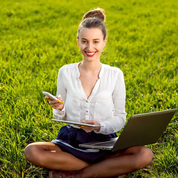 Young woman, girl working with laptop, tablet and phone in green
