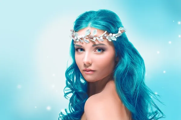 Beautiful girl with blue hair on a winter background