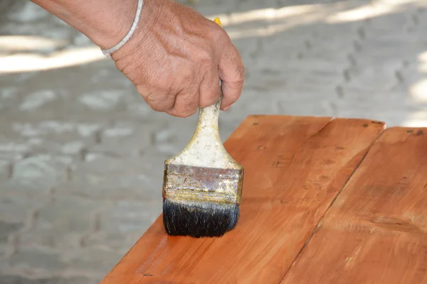 Carpenter s hands paintbrush varnish to wood table