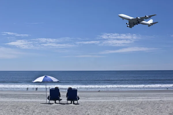 Two people on beach and flying plane