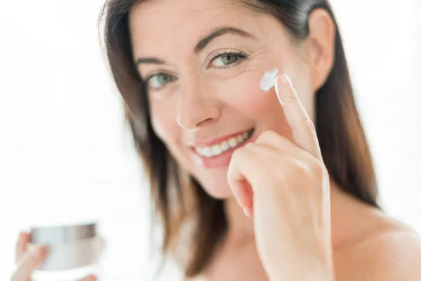 Attractive woman in her forties applying face cream