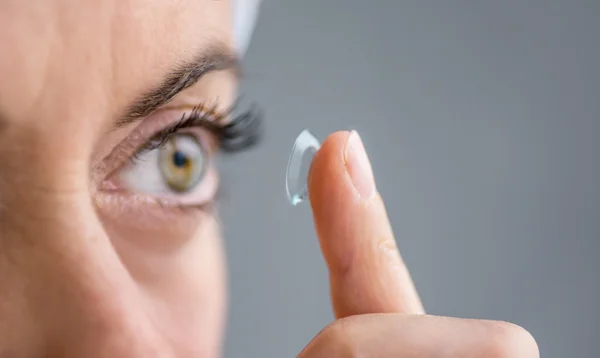 Woman in her forties inserting contact lenses
