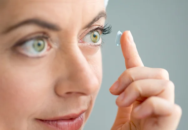 Woman in her forties inserting contact lenses