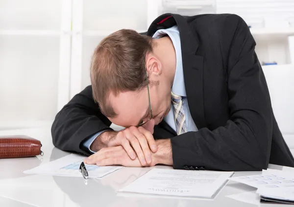 Frustrated manager with crisis sleeping at desk.