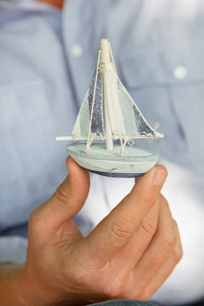 Man holding a small toy sailing boat - concept for sailing or cruising