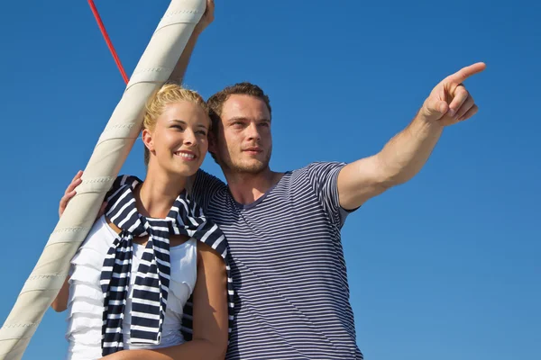 Attractive couple on sailing boat: man pointing with forefinger