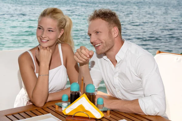 Summertime: young couple sitting in a restaurant next to the sea