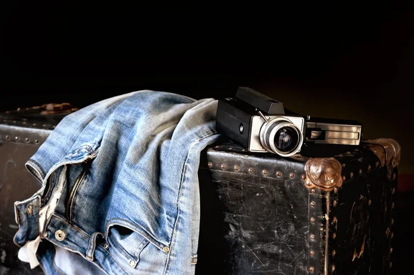 Pair of jeans and movie camera on suitcase
