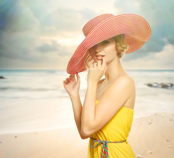 Beautiful girl in a hat enjoying the sun on the beach.