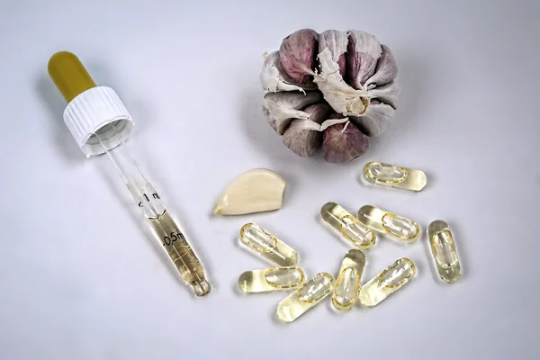 Glass dropper on capsules of garlic oil