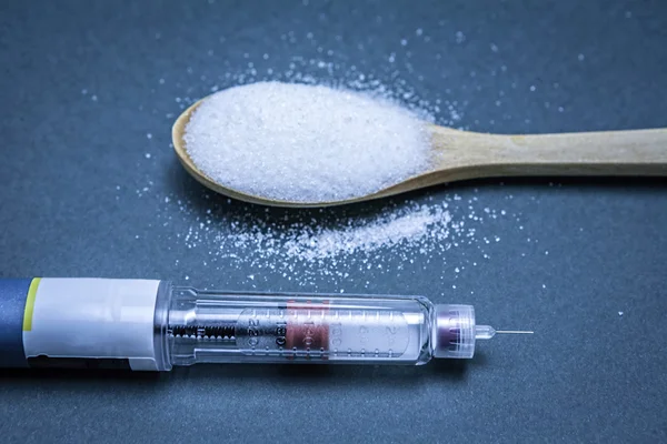 Insulin pen along with a tablespoon of white sugar