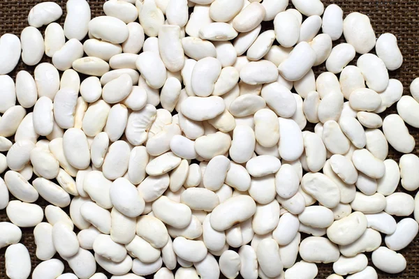 Giant white beans on sacking textured background